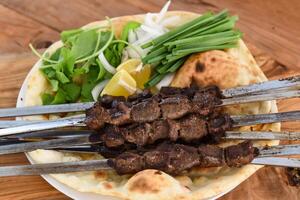 Swek of Grilled Liver tikka with bahraini bread tandoori nan, lime and salad served in dish isolated on wooden table top view middle eastern grills food photo