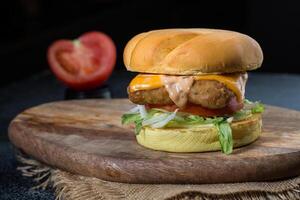 crujiente pollo emparedado o hamburguesa con repollo, tomate, lechuga hoja, Derretido queso y mayonesa aislado en de madera tablero con inmersión salsa parte superior ver de parrilla comida en oscuro gris antecedentes foto