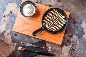 Double chocolate Chip Cookie dough with white chocolate, whipped cream, knife and fork served in dish isolated on dark background closeup top view of cafe baked dessert food photo