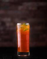 Peach ice tea with lemon and mint served in glass isolated on wooden table side view of arabic drink photo