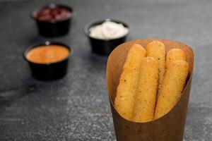 Crispy Mozzarella Cheese Sticks with dip sauce isolated on dark grey background side view of fast food sandwich photo