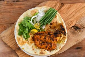 Tandoori chicken Chest with bahraini bread tandoori nan, lime and salad served in dish isolated on wooden table top view middle eastern grills food photo