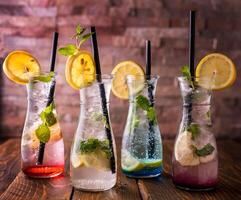 Assorted Mojito colorful collection with straw, lemon slice and mint leaves served in glass isolated on wooden table side view of arabic drink photo