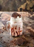 oreo malteada con chocolate y azotado crema servido en tarro aislado en oscuro antecedentes lado ver de sano bebida foto