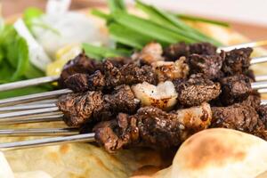 Swek of beef Tikka with bahraini bread tandoori nan, lime and salad served in dish isolated on wooden table top view middle eastern grills food photo