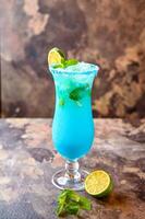 Blue Hawaiian Mojito lagoon served in cocktail with lemon and mint glass isolated on dark background side view of healthy drink photo