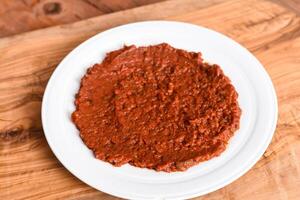 Spicy Shatta sauce or shatah with red chillies, garlic, salt and olive oil served in dish isolated on wooden table top view middle eastern appetizers food photo