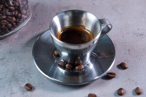 Hot Espresso serving in coffee cup with spoon and beans side view on grey background photo