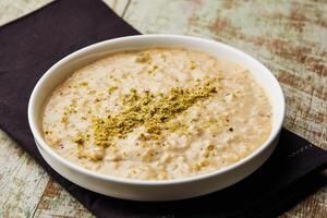 Rice pudding porridge, kheer, khir or firini sweet topping with pistachio served in dish isolated on table top view of arabic dessert food photo