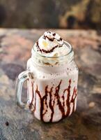 California soñando malteada con hielo crema, chocolate y azotado crema servido en tarro aislado en oscuro antecedentes lado ver de sano bebida foto