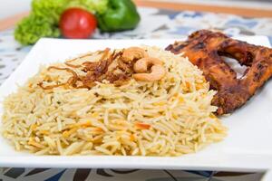 Chicken Mandi biryani rice with fried onion and cashew nuts served in dish isolated on table top view of arabic food photo