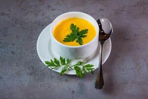 Pumpkin Soup with spoon served in dish isolated on grey background top view of bahrain food photo