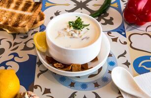 Mushroom Soup with lemon, crackers, bread and spoon served in bowl isolated on table top view of arabic food photo