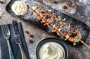 Oreos and Brownie Waffle Stick with chocolate, whipped cream, knife and fork served in dish isolated on dark background top view cafe dessert food photo