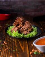 Crispy Chicken Wings with dip and lettuce leaves served in dish isolated on wooden table side view of arabic food photo