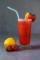 Healthy Strawberry Lemonade fresh juice served in glass with Strawberry and lemon slice straw side view on grey background photo