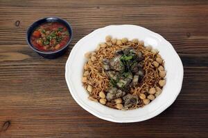 Chicken liver noodles with chickpea, tomato and chilli sauce served in dish isolated on table top view of arabic food photo