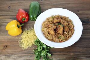 Crispy chicken noodles with bell pepper and coriander served in dish isolated on table top view of arabic food photo