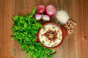 Egyptian Kishk keshj almaz with wlanuts, Coriander, and onion served in pot isolated on table top view of arabic food photo
