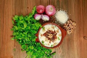 Egyptian Kishk keshj almaz with wlanuts, Coriander, and onion served in pot isolated on table top view of arabic food photo