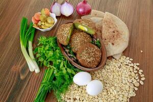 Falafel stuffed eggs with onion, spring onion and coriander served in dish isolated on wooden table top view of arabic food photo