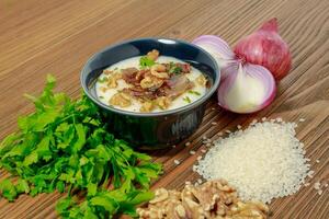 Egyptian Kishk keshj almaz with wlanuts, Coriander, and onion served in pot isolated on table side view of arabic food photo