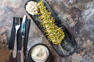 Pistachio Waffle Stick with chocolate, whipped cream, knife and fork served in dish isolated on dark background top view cafe dessert food photo