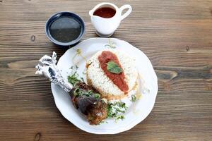 Fattah with banana or boiled rice with chicken leg piece with sauce served in dish isolated on wooden table top view of arabic food photo