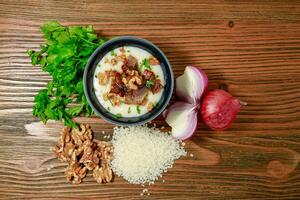 Egyptian Kishk keshj almaz with wlanuts, Coriander, and onion served in pot isolated on table top view of arabic food photo