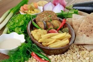 Egyptian Dynamite breakfast platter with flafel, marinated fried eggplant, mashed potato, hummus, foul, beans, pita bread, salad and coffee drink isolated on table side view photo