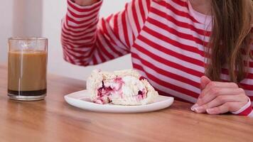 donna mangiare meringa rotolo torta con crema e lamponi seduta nel il cucina o cenare camera video