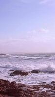 azul cielo, fuerte olas y salpicaduras estrellarse y salpicaduras en el rocas en un soleado día y áspero mar. poderoso mar olas rotura terminado rocas en playa megas limnionas, Quíos, Grecia video