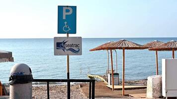 chios, Griekenland 27.09.2023 gehandicapt persoon parkeren teken De volgende naar strand. speciaal plaatsen voor auto's behoren gehandicapt mensen. rolstoel parkeren symbool. ondersteunend milieu voor mensen met speciaal behoeften video