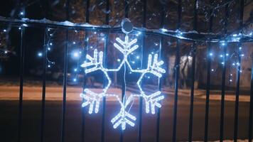 Neon Christmas snowflake. Beautiful Christmas decoration on the fence. Neon illumination of the winter city for the new year. New Year's mood. video