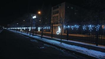 schön Weihnachten Dekoration auf das Zaun. Neon- Erleuchtung von das Winter Stadt zum das Neu Jahr. Neu Jahre Stimmung. Anmerkungen und Schneeflocken. ein gehen durch das Nacht Stadt video