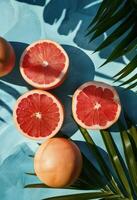 pomelos, naranjas, y palma hojas en azul superficie foto