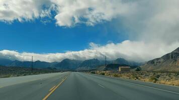 Open Highway in Desert Landscape, A quiet highway stretches into the distance, flanked by desert mountains and a cloudy blue sky. video