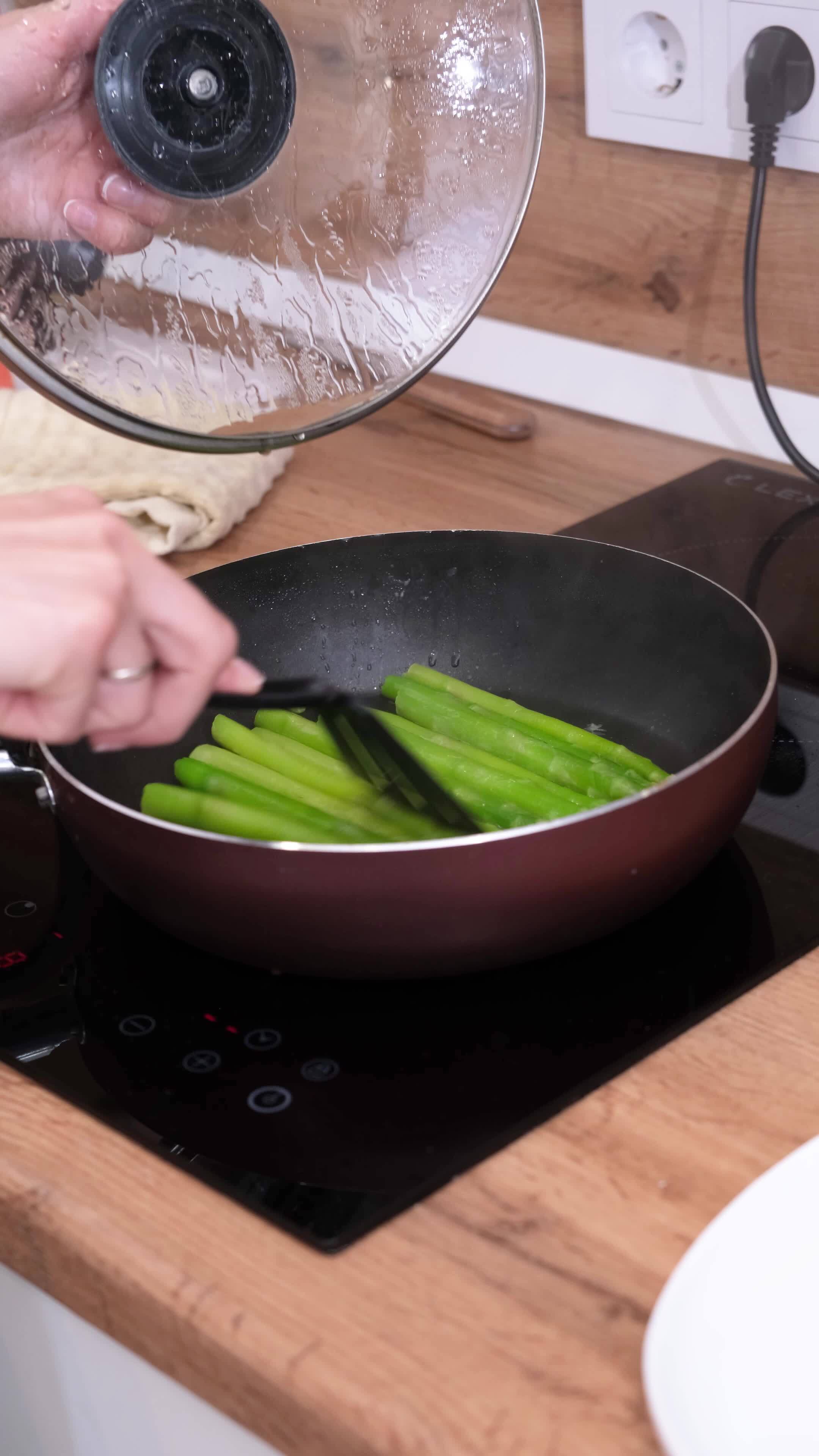 Healthy food woman cooking fresh asparagus in a pan in the kitchen