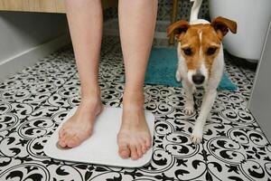 Woman checking her weight on weighing scales in bathroom photo