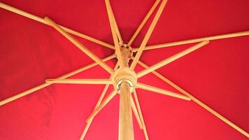 Crossing wooden umbrella structure create an abstract pattern on red background photo