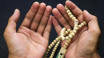 Overhead view of hands holding prayer beads with black background. photo