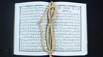 Composition with Holy Qur'an, prayer beads on black background and space for the text. photo