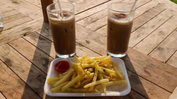 french fries, sauce, milk, chocolate on a wooden table with natural scenery as a background. photo