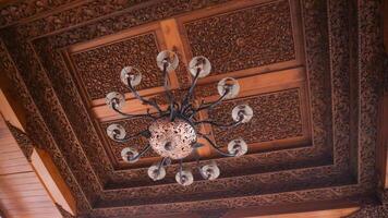 Beautiful retro chandelier on wood carving ceiling in traditional javanese house interior. photo