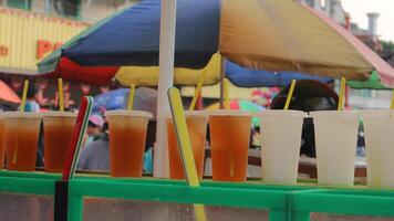 neat arrangement of iced tea and orange juice in a cup sold on the side of the road. photo