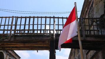 The red and white Indonesian flag tied to a bamboo pole fluttering by wind. independence day concept photo