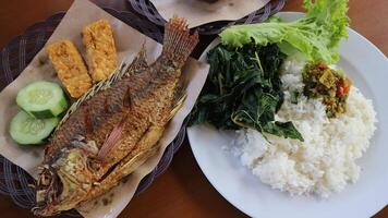 Fried Tilapia Fish Lalapan Nila Goreng with white rice, chili sauce and vegetables photo