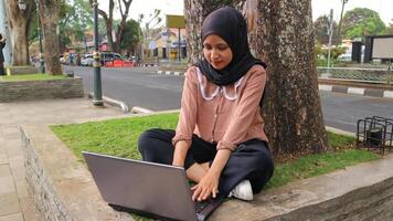 retrato de árabe negocio mujer trabajando en ordenador portátil sentado a ciudad parque. foto