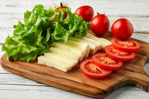 AI generated Wooden cutting board with sliced cheese, fresh green lettuce, and ripe tomato wedges on a white wooden table photo