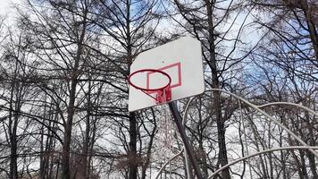 un' pallacanestro cerchio nel il cortile con un' strappato rete. lancio il palla in il cerchio video